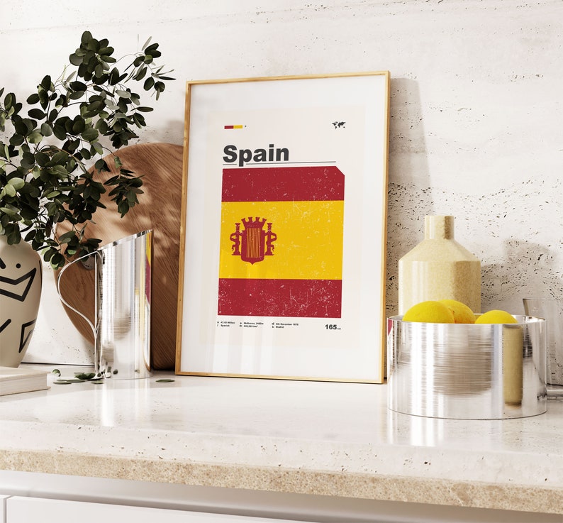 K&ouml;nnte beinhalten: Ein gerahmter Druck mit wei&szlig;em Hintergrund und dem Wort "Spanien" in schwarzem Text. Der Druck zeigt eine rot-gelbe Flagge mit einem Wappen in der Mitte. Die Flagge hat einen abgenutzten, Vintage-Look.