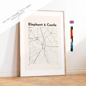 May include: A framed wall art print featuring a minimalist black line map of the Elephant & Castle area in London on a light cream background. The text Elephant & Castle is printed in bold black letters at the top of the map illustration.