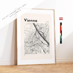 May include: A framed wall art print featuring a black and white street map of Vienna, Austria. The map is set against a light beige background with the text Vienna and /Austria printed at the top. A small red and white flag icon is visible.