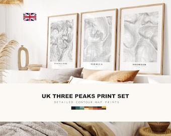 May include: Three framed prints featuring detailed contour maps of Scafell Pike, Ben Nevis, and Snowdon. The prints are in neutral tones and are displayed above a bed with pillows and a blanket. The text "UK THREE PEAKS PRINT SET" is visible.