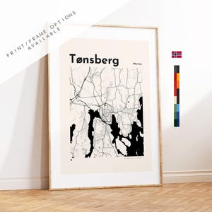 May include: Framed map print of Tønsberg, Norway, in black and white. The map features the city's layout with roads and waterways, set against a cream background. The text "Tønsberg" is displayed at the top, with "Norway" below. The frame is a light wood color.