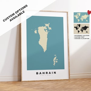 May include: A teal blue poster with a beige outline of the country of Bahrain. The poster has the word "BAHRAIN" printed in black at the bottom and the coordinates "26.0667° N, 50.5577° E" printed in smaller black font. The poster is framed in a light wood frame. The poster is hanging on a white wall. There are two world maps in the background, one with a white outline and one with a black outline. The text "DIFFERENT COLOURS", "CUSTOM TEXT", and "CHOOSE A LOCATION" is printed in black on a white background.