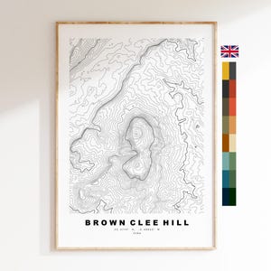 May include: A framed topographic map print of Brown Clee Hill featuring black contour lines on a white background. The text reads Brown Clee Hill, 52.4749 N, -2.60063 W, 540m. A small Union Jack flag and a vertical color palette strip are included.