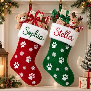 May include: Two Christmas stockings, one red and one green, featuring white faux fur cuffs embroidered with the names Sophia and Stella. The stockings are decorated with white paw prints and snowflakes, and filled with plush toys and gifts.
