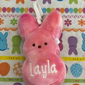 May include: Pink plush Peeps bunny with a white clip and the name "Layla" embroidered on the front.