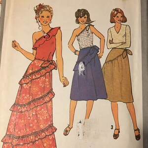 May include: A vintage sewing pattern for a women's skirt and top. The pattern is for size 10 and features three different styles. The first style is a long, red skirt with a floral print and a ruffled hem. The second style is a shorter, blue skirt with a ruffled hem. The third style is a brown skirt with a ruffled hem. All three styles feature a one-shoulder top.