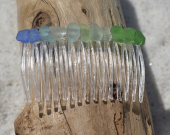 May include: A clear plastic comb with a row of sea glass beads in shades of blue and green.