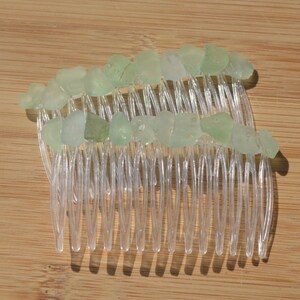 May include: A clear plastic hair comb with light green sea glass pieces attached to the teeth.