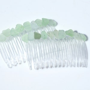 May include: Two clear plastic hair combs with light green sea glass pieces attached to the top of each comb.