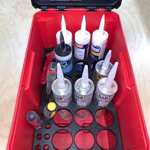 May include: Red plastic storage case with a black foam insert. The case is filled with tubes of caulk and sealant. The tubes are labeled "DAP" and "Load".