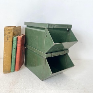 May include: Two olive green metal storage bins stacked on top of each other. The bins have an open front and a lip at the top. To the left are three vintage books with titles including "Cape Cod Stories".
