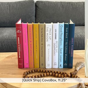 May include: A set of ten hardback books with colourful spines and white titles. The books are arranged vertically on a wooden surface. The titles of the books are: "Someone to Watch Over Me", "On the Rooftop", "Palm Beach", "Double Jeopardy", "The Sun Walks Down", "The Moon", "Pack Up", "Before She Disappeared", "Good Neighbors", and "Small Pleasures".