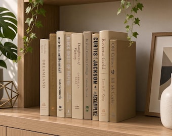 May include: A row of books with neutral-toned spines arranged on a light wood shelf. Titles include Dreamland, One in a Millennial, Black Ghost of Empire, Daughters of Victory, An Irish Country Cottage, Curtis Jackson The Accomplice, Riviera Gold, and Old Crimes.