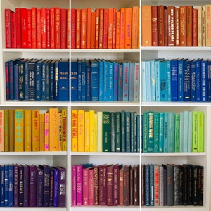 May include: A bookshelf filled with colorful books, organized by color. The books are arranged in rows, with each row containing books of a single color. The colors include red, orange, yellow, green, blue, purple, and black.
