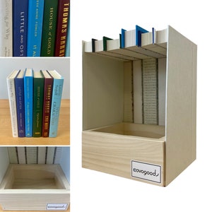 May include: A white wooden box with a small wooden drawer. The box has a cutout on the top and is filled with books. The box has a label on the bottom that says "covogood".