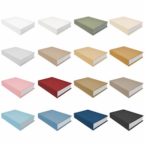 May include: A collection of sixteen rectangular decorative storage boxes designed to resemble closed books. Each box features a solid-colored exterior cover in various shades including white, green, beige, pink, red, blue, and black, with white edges.