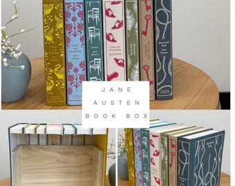 May include: A collection of seven Jane Austen books with colorful, patterned spines including yellow, blue, teal, white, green, pink, and dark blue. The books are arranged upright and also shown as a hollow wooden box structure with book spines.