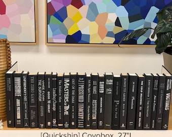 May include: A collection of twenty-four hardcover books with black spines and white text, arranged in a single row on a shelf. The titles include More Than Courage, Invisible, Unfriendly Skies, The Zero Game, The Survivor, Good to Great, and Victims.