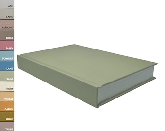 May include: A sage green hardcover book positioned at an angle, displaying its smooth front cover and white page edges. To the left, a vertical color chart lists various shades including white, pearl, ash, sand, almond, beige, taffy, powder, lake, sage, ivory, wheat, camel, gold, taupe, gray, and black.