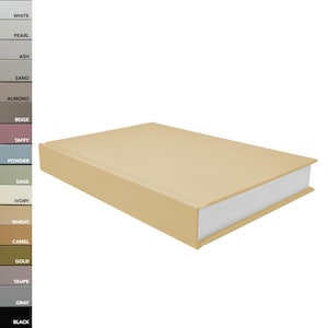 May include: A closed, hardback book with a beige cover. The book is lying on its side with the spine facing up.