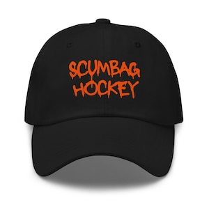 Peut inclure: Casquette de baseball noire avec le texte orange "SCUMBAG HOCKEY" en police dégoulinante. La casquette a une visière incurvée et une coupe structurée. Un chapeau classique pour les fans de sport.