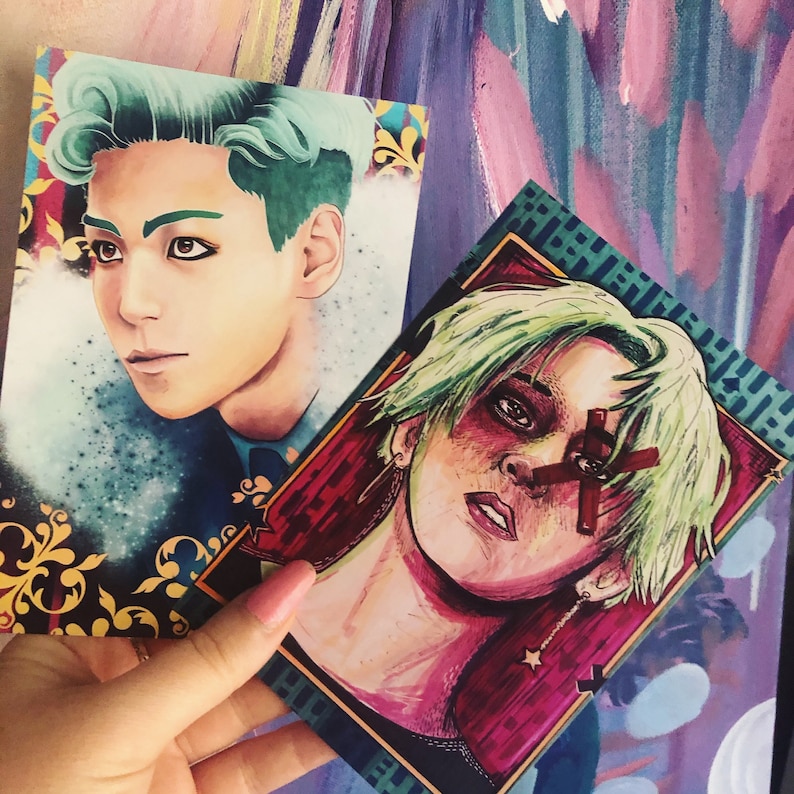 May include: Two illustrated cards featuring portraits of men with green hair. The first card has a blue and gold background with ornate designs. The second card has a red and black background with a star and a red cross.