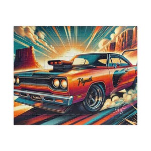 May include: A vibrant jigsaw puzzle depicting a classic Plymouth muscle car in a desert scene. The car is predominantly orange with black details and the word "Plymouth". The background shows a sunset and rock formations.