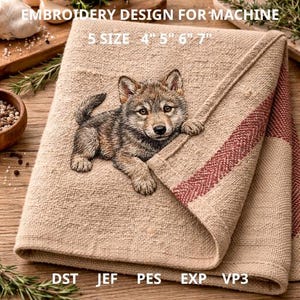 Puede incluir: Una toalla de lino beige con un bordado detallado de un cachorro de lobo. La toalla tiene un diseño de rayas rojas en el borde. El texto en la imagen dice "EMBROIDERY DESIGN FOR MACHINE" y "5 SIZE 4" 5" 6" 7"", junto con abreviaturas de tipo de archivo.