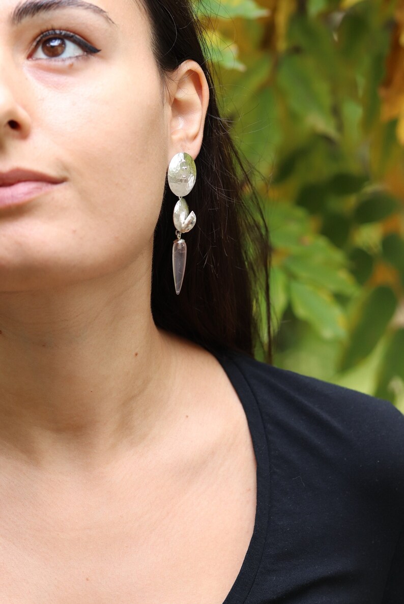 Ragazza che indossa orecchini pendenti con dischetti e pendoli di quarzo rosa.