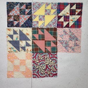 May include: Nine colorful quilt blocks with various patterns and designs. The blocks feature floral, plaid, and geometric patterns in shades of blue, yellow, red, and pink. Each block is approximately 10 inches square.