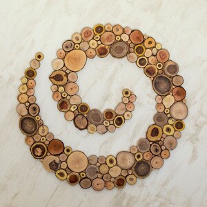It is an original artwork in the form of a spiral on the wall. The artwork is handmade from slices of Mediterranean tree branches and has great beauty and personality due to the shape and shades of the slices. Sizes: 20, 24, 28, 32, 36, 40 in.