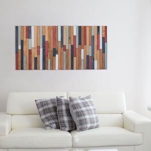 The image shows this wall art sculpture on the wall decorating a modern and elegant living room. The combination of cold and warm colours and the different geometric pieces, makes it a very balanced artwork.