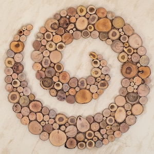 It is an original artwork in the form of a spiral on the wall. The wood spiral is handmade from slices of Mediterranean tree branches and has great beauty and personality due to the shape and shades of the slices. Sizes: 20, 24, 28, 32, 36, 40 in.