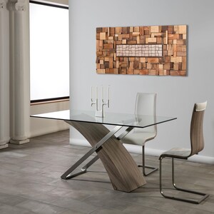 May include: A modern dining room set featuring a glass-top table with a unique wooden and metal base. Two chairs with white leather seats and wooden backs are positioned around the table. A wooden art piece hangs on the wall, and a candle holder with three candles sits on the table.