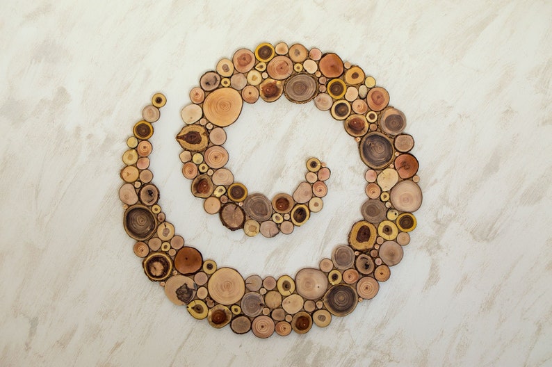 It is an original artwork in the form of a spiral on the wall. The artwork is handmade from slices of Mediterranean tree branches and has great beauty and personality due to the shape and shades of the slices. Sizes: 20, 24, 28, 32, 36, 40 in.