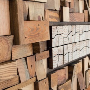 The side image shows in detail the volume and shape of the recycled wood pieces that make up this horizontal wall sculpture, as well as their beautiful imperfections. This eco-friendly piece is painted in warm tones. Dimensions: 48 x 24 in.