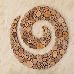 It is an original artwork in the form of a spiral on the wall. The artwork is handmade from slices of Mediterranean tree branches and has great beauty and personality due to the shape and shades of the slices. Sizes: 20, 24, 28, 32, 36, 40 in.