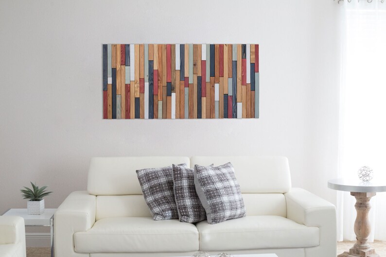 The image shows this wall art sculpture on the wall decorating a modern and elegant living room. The combination of cold and warm colours and the different geometric pieces, makes it a very balanced artwork.