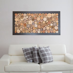 May include: A rectangular wall art piece featuring a mosaic of numerous circular wood slices in various shades of brown, tan, and cream. The wood slices are arranged closely together and mounted within a solid black rectangular frame.