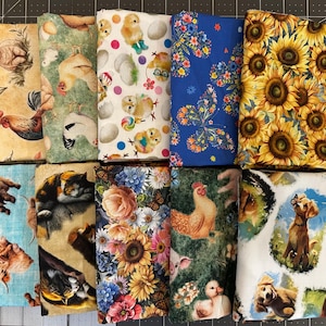 May include: Ten folded fabric bolts arranged in two rows. Patterns include farm animals like chickens, roosters, and lambs, a cat, a dog, sunflowers, butterflies, and floral designs. The fabrics feature vibrant colors including yellow, blue, green, and white.