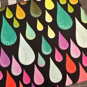 May include: A black fabric featuring a repeating pattern of teardrop shapes in various colors including yellow, orange, teal, light blue, pink, and red. Each teardrop contains a white dotted texture that fades toward the center of the shape.