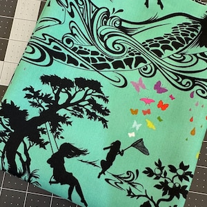 May include: A mint green fabric featuring a black silhouette print of a person on a swing under a tree, a person with a butterfly net, and swirling abstract patterns. A cluster of small, colorful butterflies in pink, orange, and yellow accents the scene.