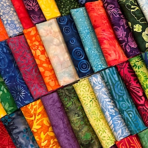 May include: A collection of colorful fabric scraps with various patterns, including floral, geometric, and abstract designs. The fabrics are arranged in a rainbow pattern, with each scrap folded in half.