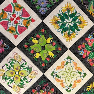 May include: A colorful quilt featuring a repeating pattern of embroidered fruit and floral designs. The quilt showcases watermelons, oranges, strawberries, pears, lemons, avocados, and sunflowers, set against a black and white checkered background.