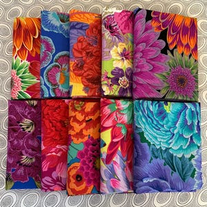 May include: A collection of ten folded fabric swatches arranged in two rows, each featuring vibrant, multi-coloured floral patterns with shades of magenta, orange, blue, green, purple, and red, showcasing intricate botanical designs.