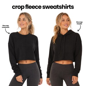 two women wearing black crop fleece sweatshirts, one with a crew neck and the other with a hoodie.