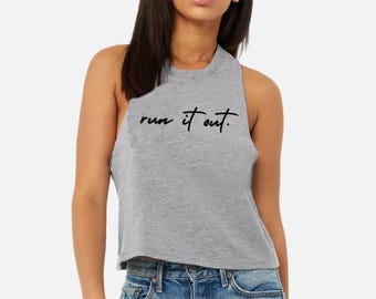 May include: A heather gray sleeveless crop top featuring a crew neckline and the black cursive text "run it out." printed across the chest. The garment has wide arm openings and a straight hemline, paired with blue denim jeans.