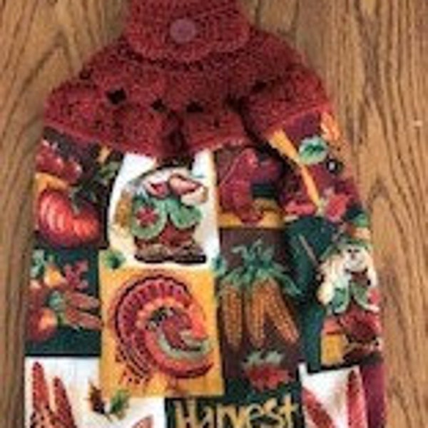 Thanksgiving hanging kitchen towel with a crocheted top.  It has a turkey, scarecrows, corn, pumpkins, cornucopia, etc. The  top is rust.