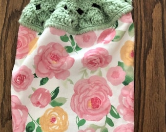 Hanging kitchen towel with a crocheted top.  The pattern pink and yellow roses on white background.  The crocheted top is light green.