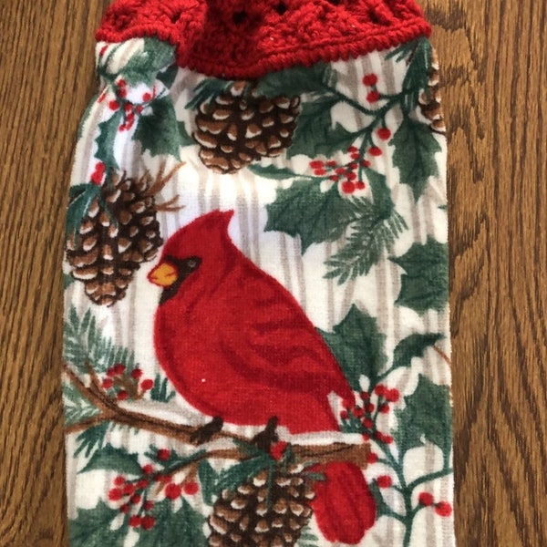 Christmas hanging kitchen towels with a crocheted top.  The pattern is a cardinal sitting on pine branches among the pinecones on white.